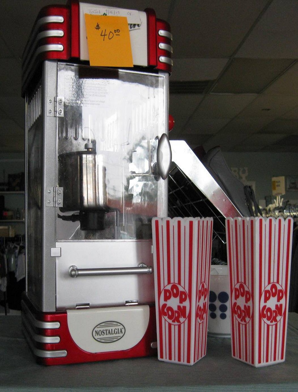 Vintage Nostalgia popcorn machine with red accents and striped popcorn cups in front.
